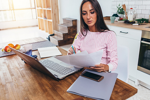 Woman looking at documents at a laptop